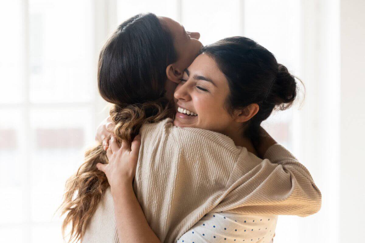 Two women celebrating the process of forgiveness with a hug
