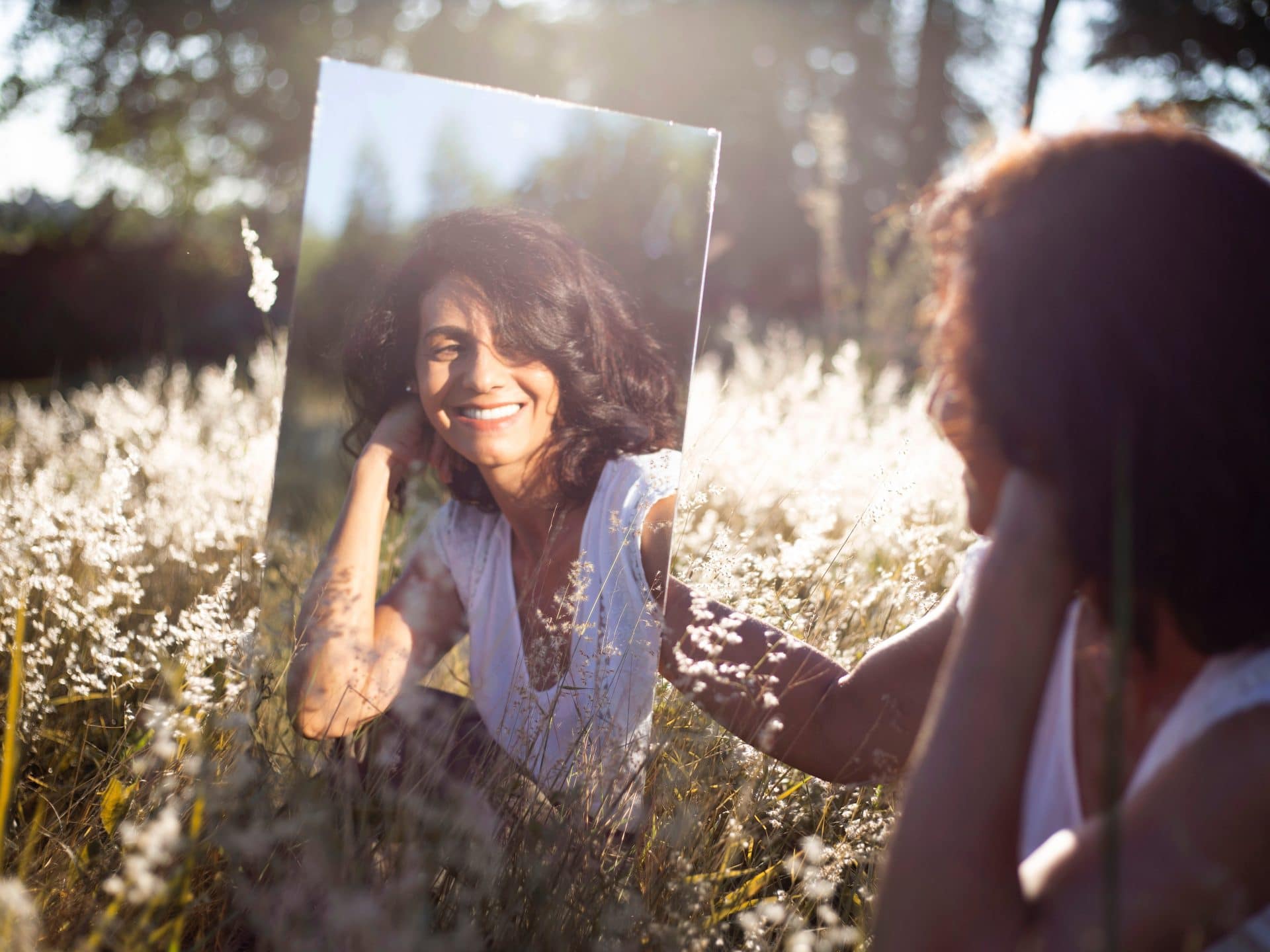 A happy woman outdoors, smiling in a mirror